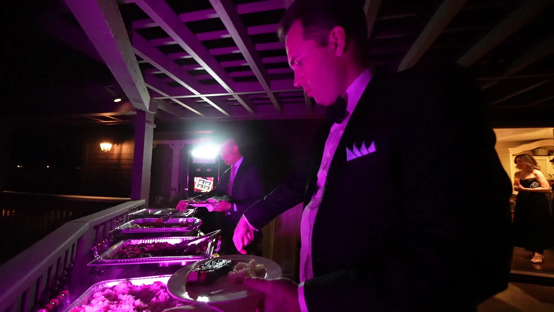 Attendant tending a hot buffet line at an evening event in downtown Santa Cruz