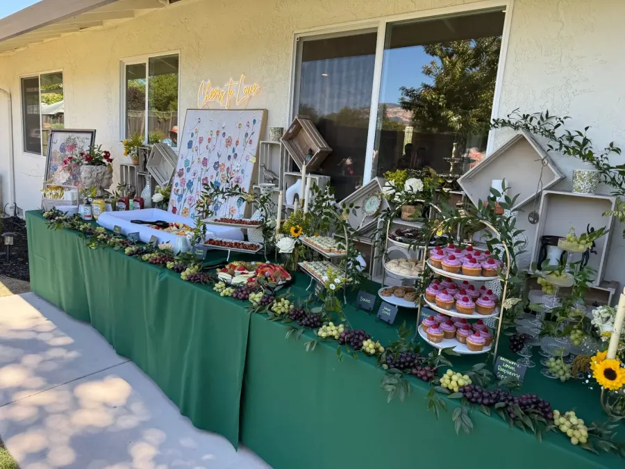 Shower sweets and grazing display softened with roses and trailing greenery set among cupcakes and fruit — shower floral styling from Scotts Valley catering