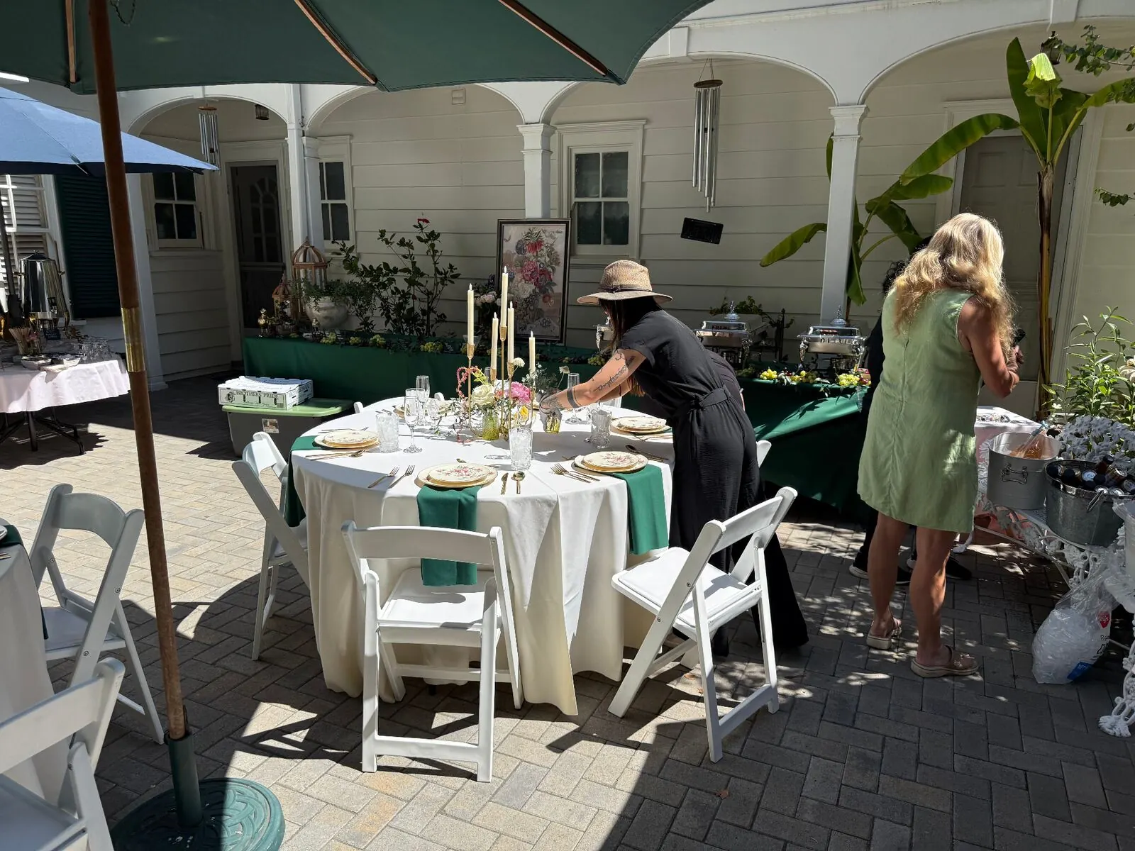 Courtyard rounds in emerald linens finished with compact arrangements, stemware and full settings — floral and rental styling for Santa Cruz catering receptions