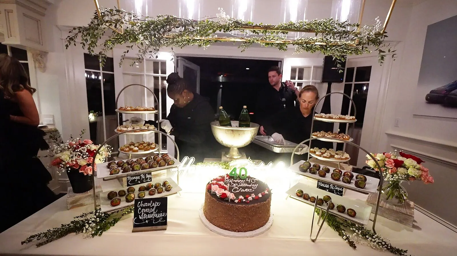 Dessert table of dipped strawberries, layered cake and petite sweets accented with fresh blooms on tiered risers — dessert florals for Aptos catering celebrations
