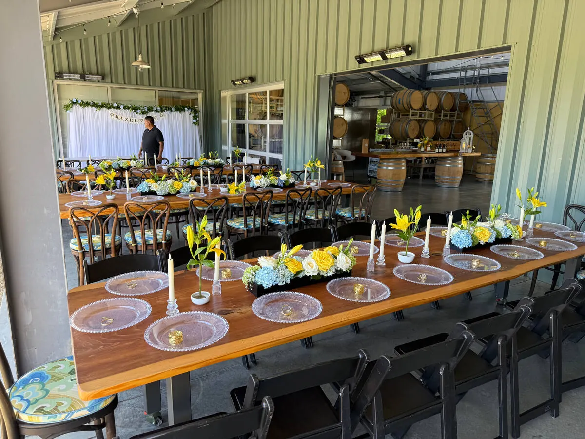 Banquet table lined with lily, hydrangea and white rose arrangements between slim taper candles — centerpiece design for Scotts Valley catering dinners