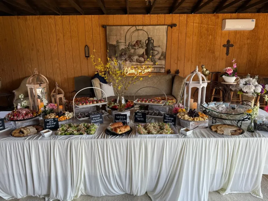 Grazing spread of cured meats, tea sandwiches and fruit tarts broken up by low bud vases down its length — floral-styled grazing for Soquel catering gatherings