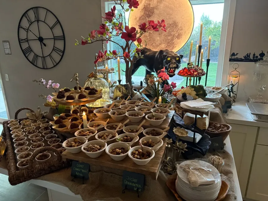 Mediterranean buffet of shawarma chicken, kebob and mezze framed by low seasonal arrangements along the table edge — buffet florals for Watsonville catering dinners